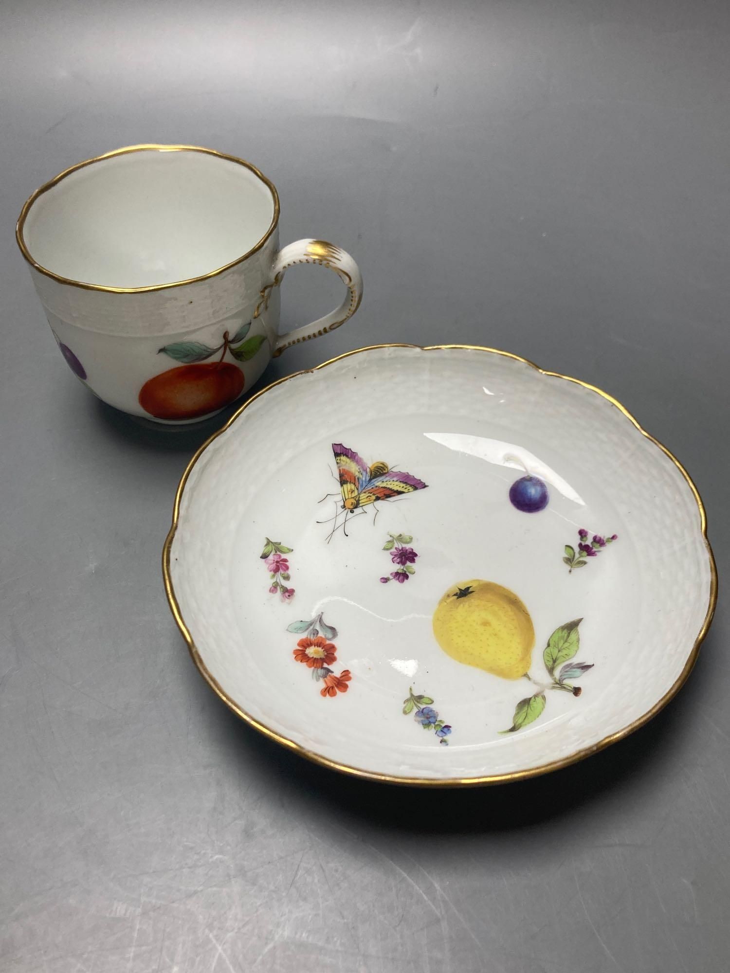 A Meissen cup and saucer, factory seconds, decorated with fruit and butterflies and lined with gilt